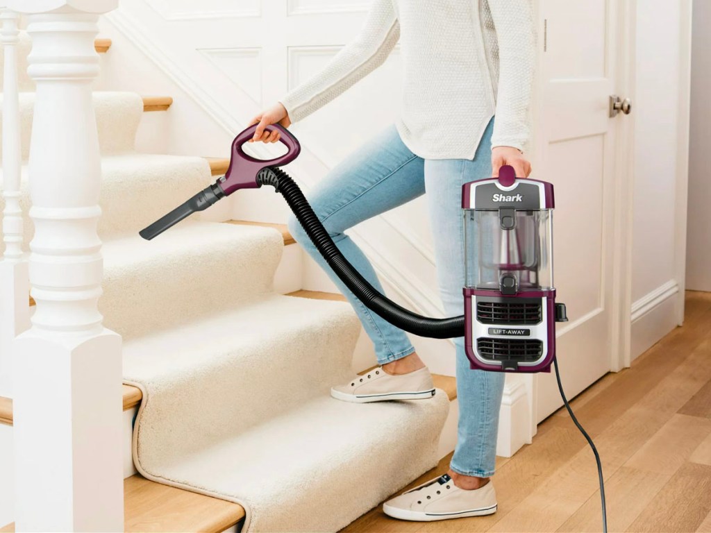 woman vacuuming with shark lift away vacuum on stairs