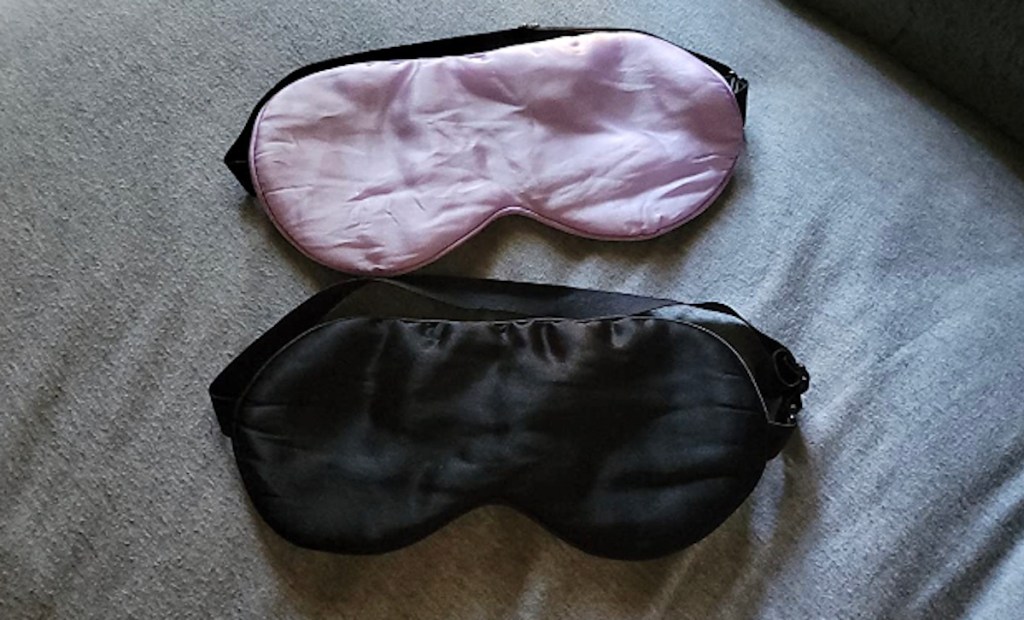 pink and black silk sleep mask on gray bedding