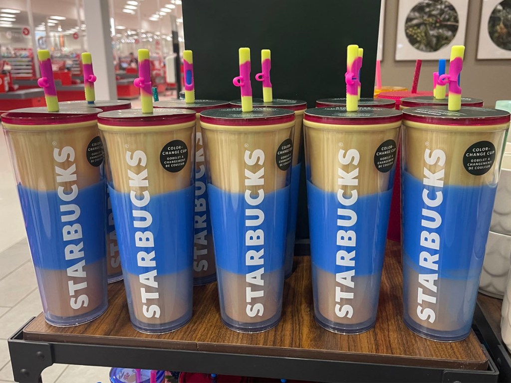 blue and gold starbucks cups with straws lined up on the shelf