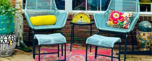 teal patio chair, stool and table set on porch with yellow and flower pillows