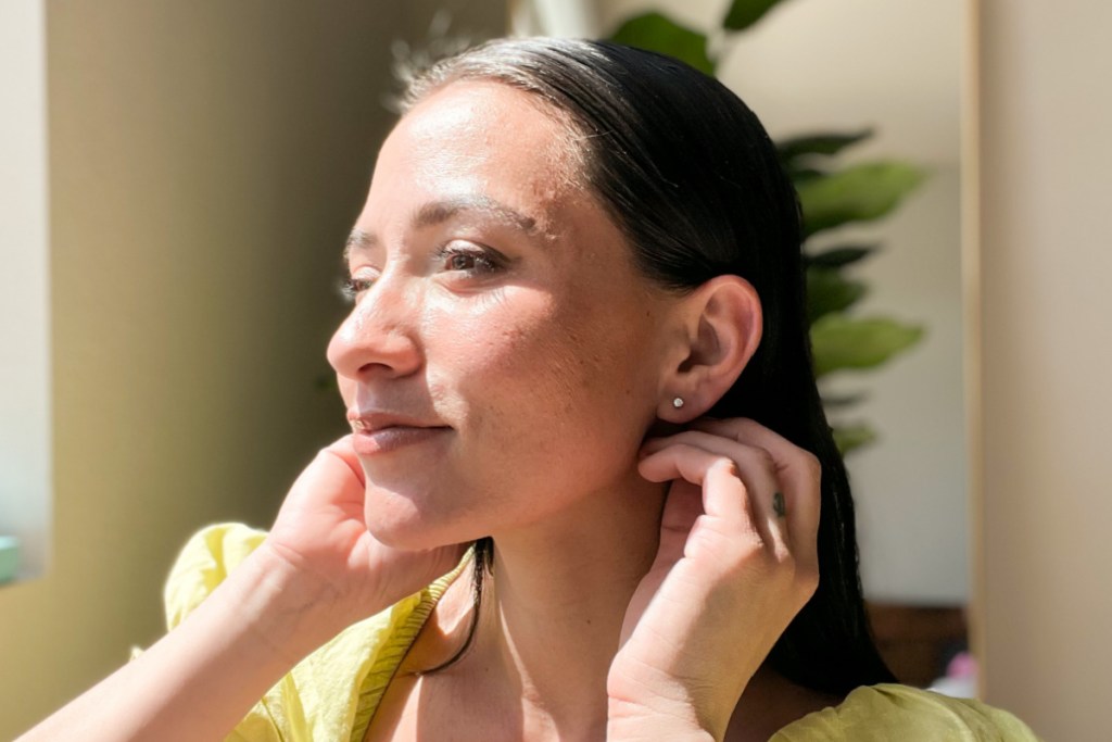 woman tucking hair behind ear showing diamond stud earring