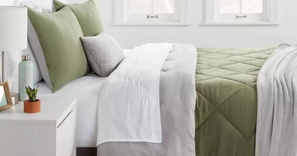 white throw over olive comforter with white sheets and matching olive pillows on bed in bedroom