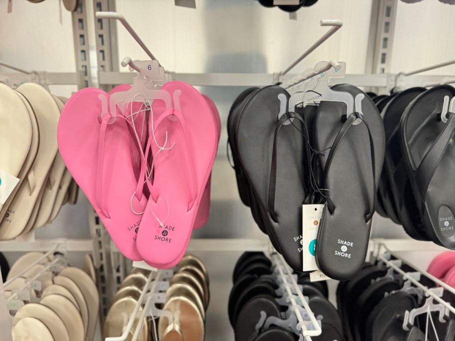 women's pink, black and tan flip flops on a store display rack