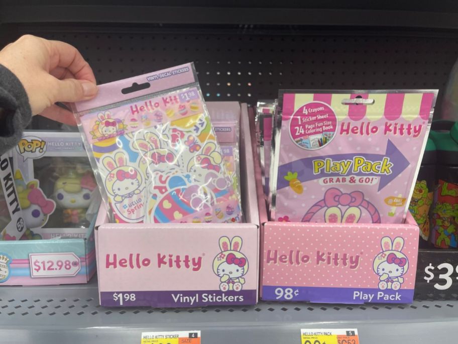 hand reaching for packs of Hello Kitty stickers in box on shelf