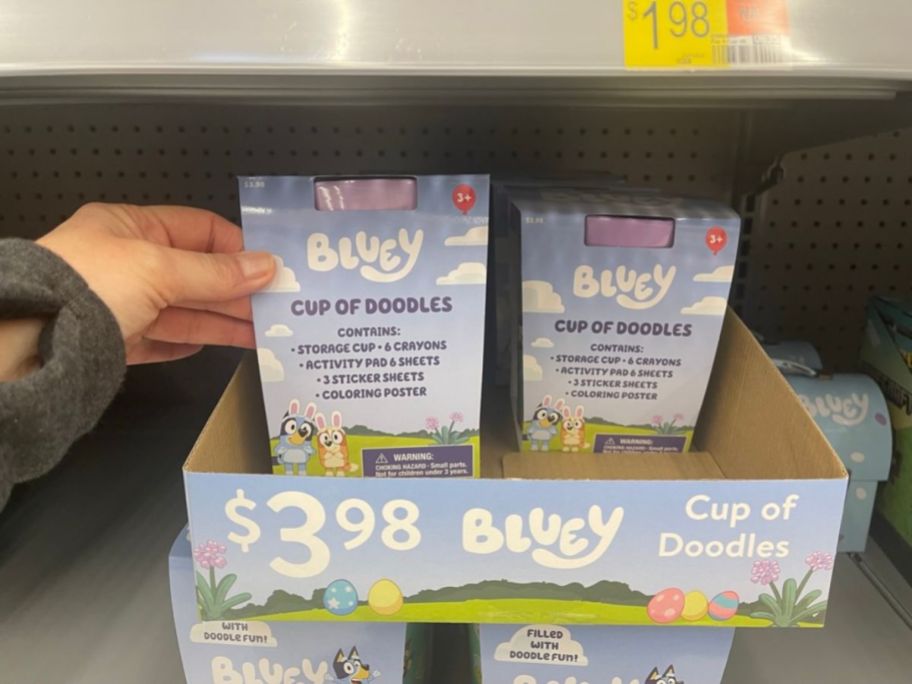 hand reaching for a display shelf in store with Bluey Easter Cup of Doodles Art Kits