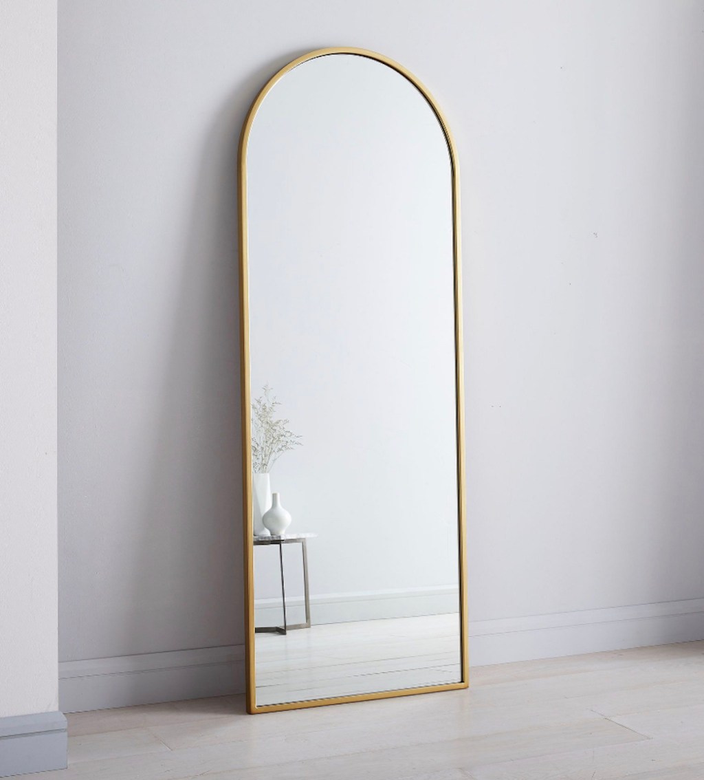 gold arched floor mirror in gray room