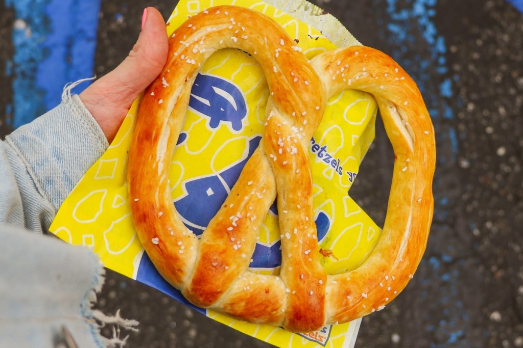 holding a soft pretzel on a yellow bag