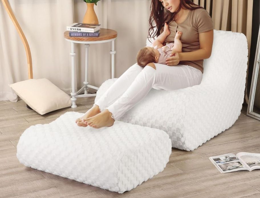 a woman holding a baby sitting on a white beanbag chair