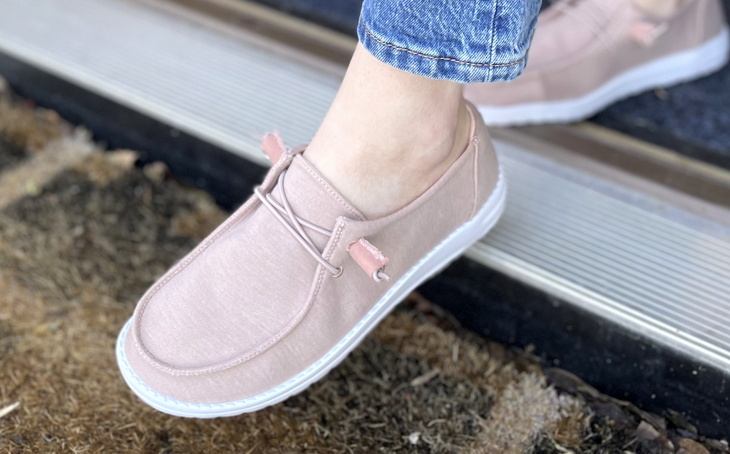 Person wearing a pair of pink slip on shoes