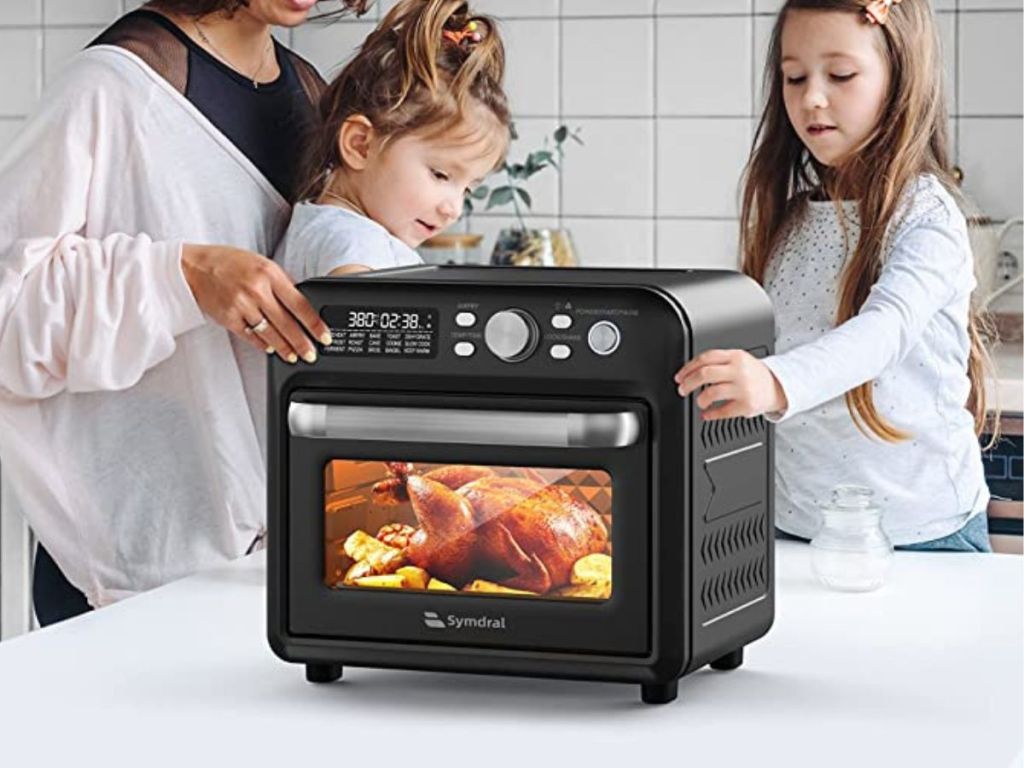 woman and 2 girls gathered around air fryer
