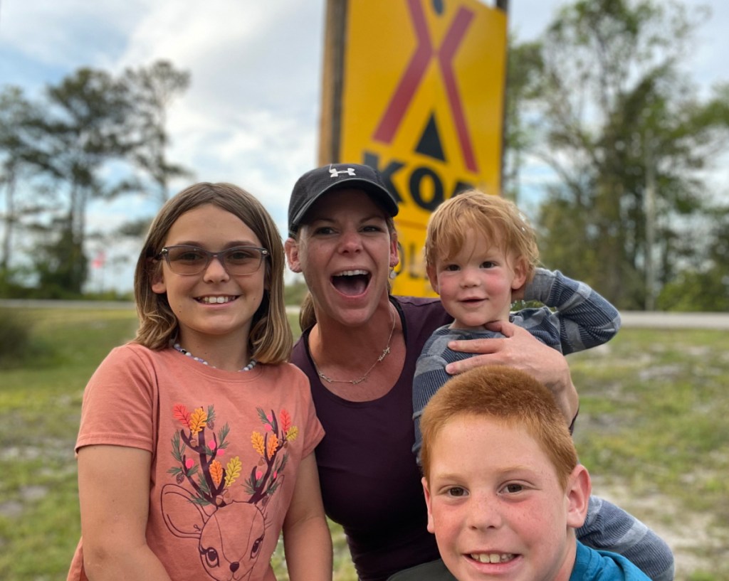 A family posing in front of a KOA sign