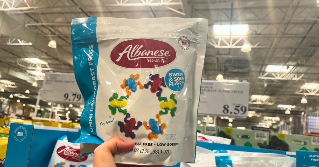 a hand holding a bag of Albanese gummy frogs in a costco store