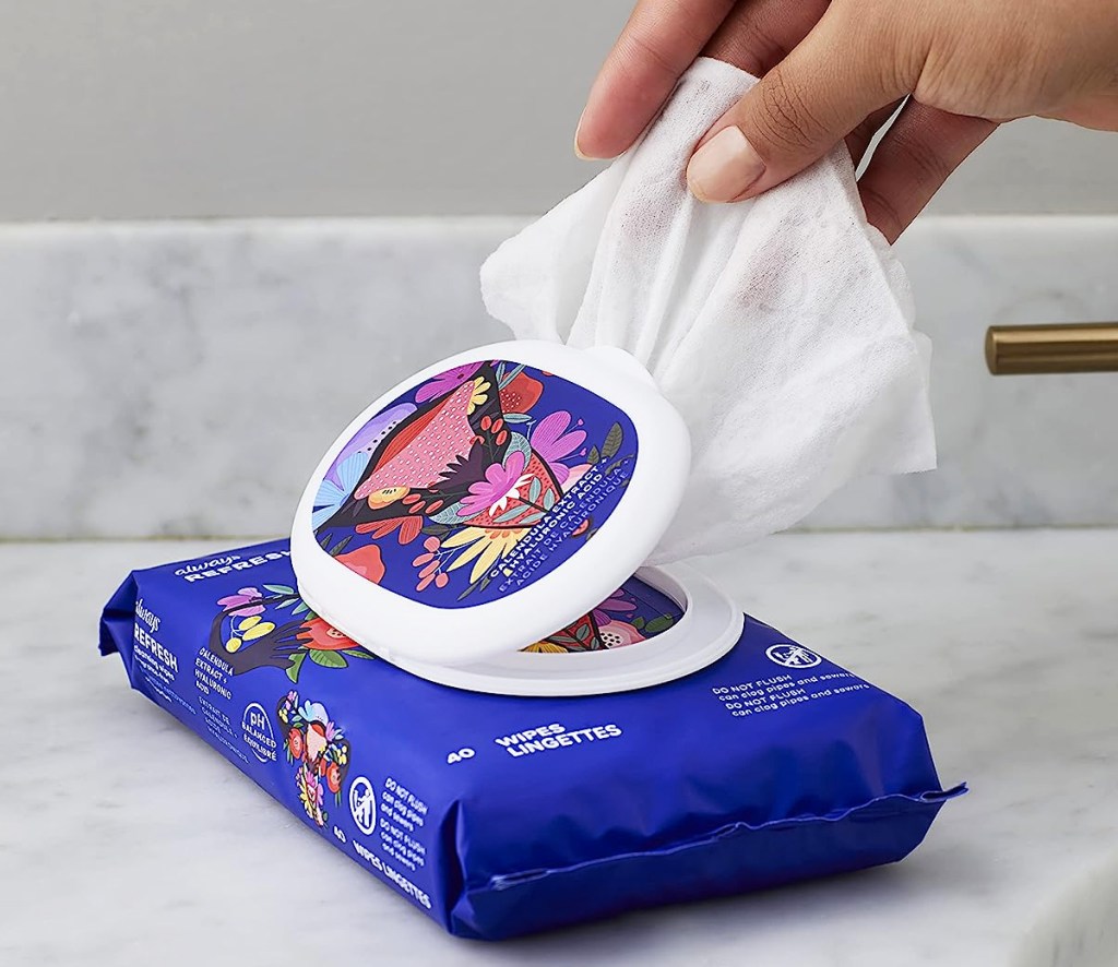 hand grabbing a wipe from a blue package on bathroom counter
