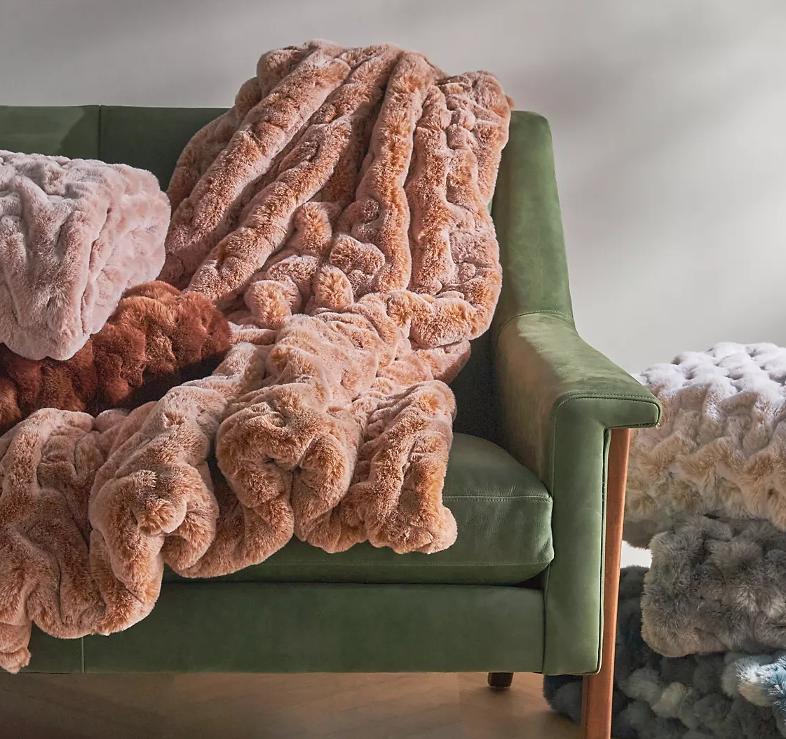 Faux fur blankets draped over a green couch