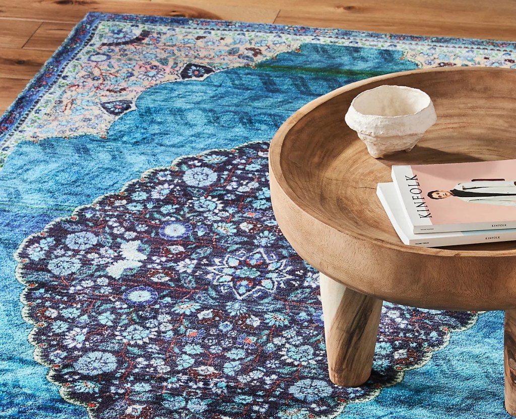 Coffee table sitting on a blue rug with a design in the middle