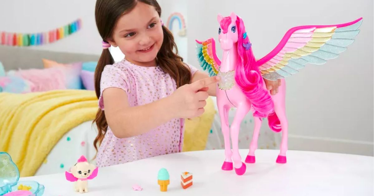 a little girl playing with the Barbie A Touch of Magic Pink Pegasus with Puppy, Lights and Sounds stock image