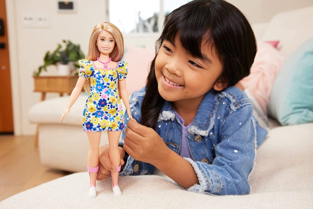 Girl playing with Matte's first Barbie Doll that has down syndrome