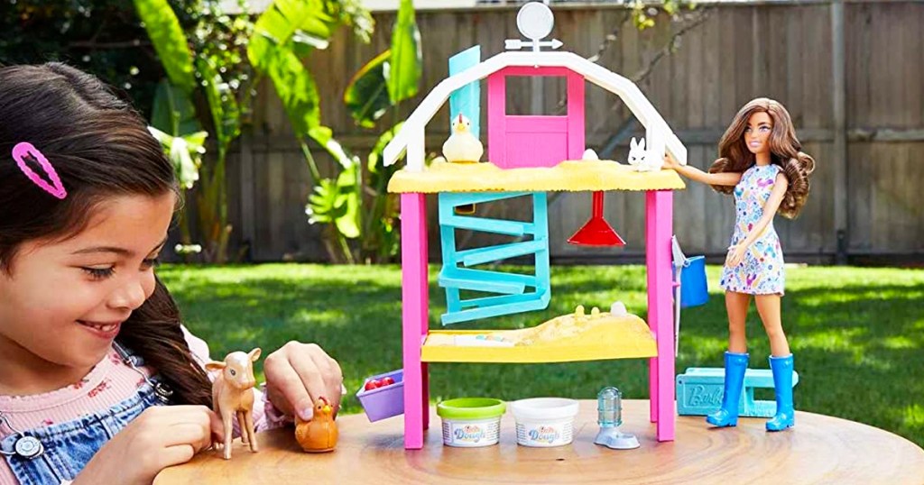 girl playing with Barbie Hatch & Gather Egg Farm playset