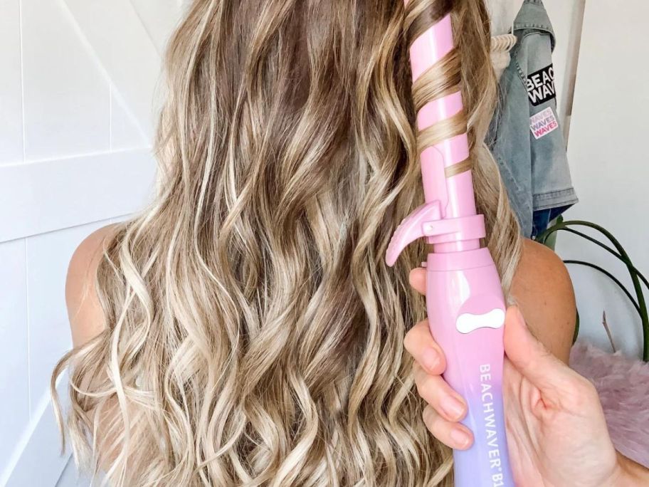 Woman curling hair with a Pink Sunset Beachwaver