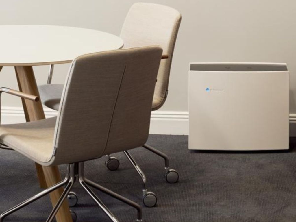 Blueair Pro M Air Purifier next to a table with rolling desk chairs