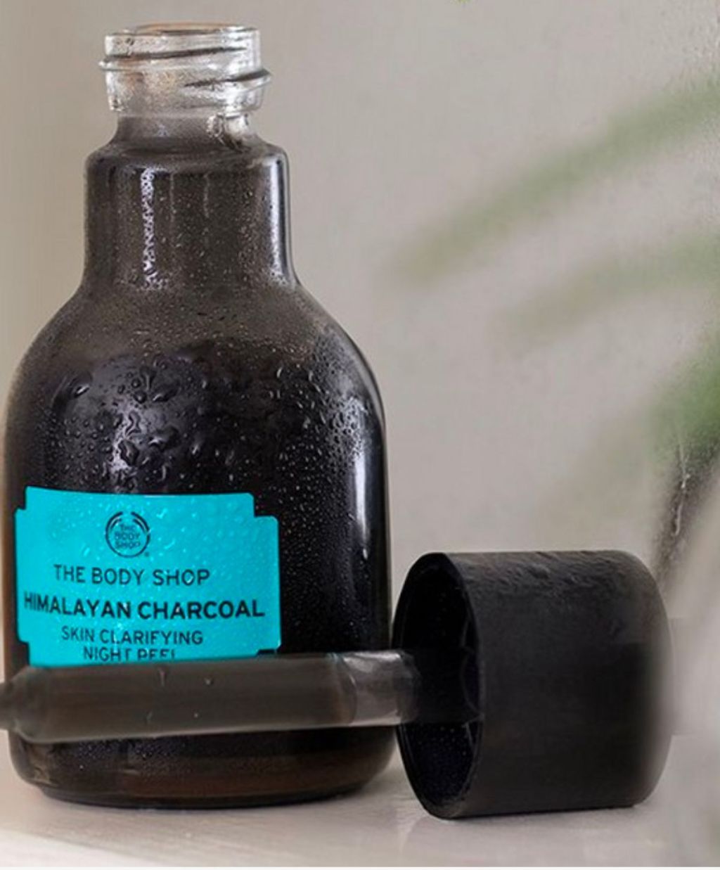 close up of a bottle of Body shop himalayan charcoal night peel sitting on a bathroom counter