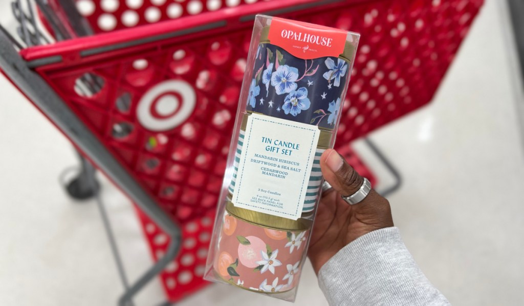 Woman holding a candle gift set in front of a target cart