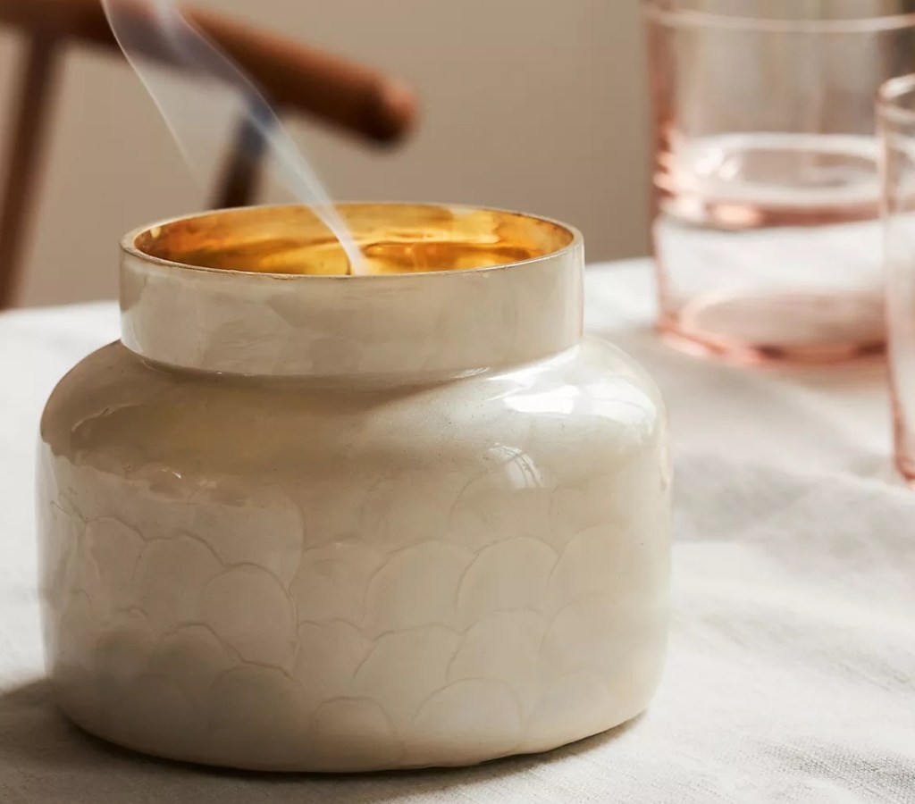 White candle jar with smoke coming out the top