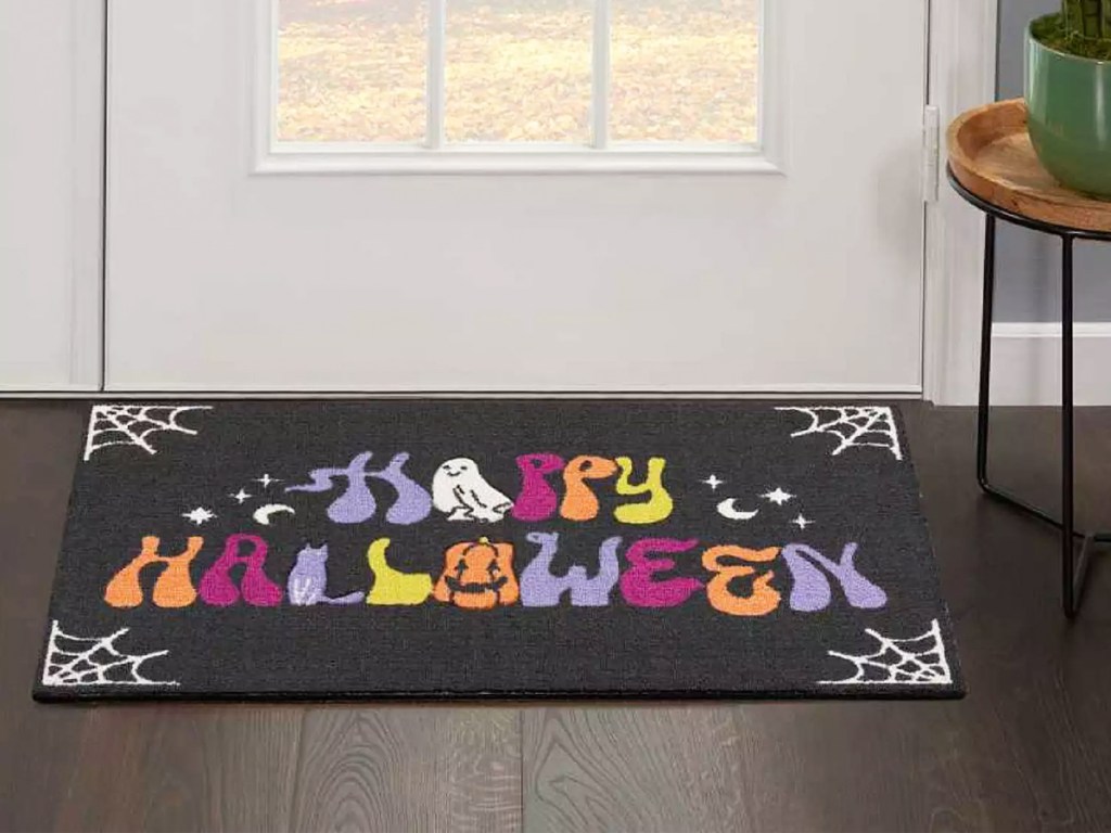 black accent rug that says happy halloween in various colors