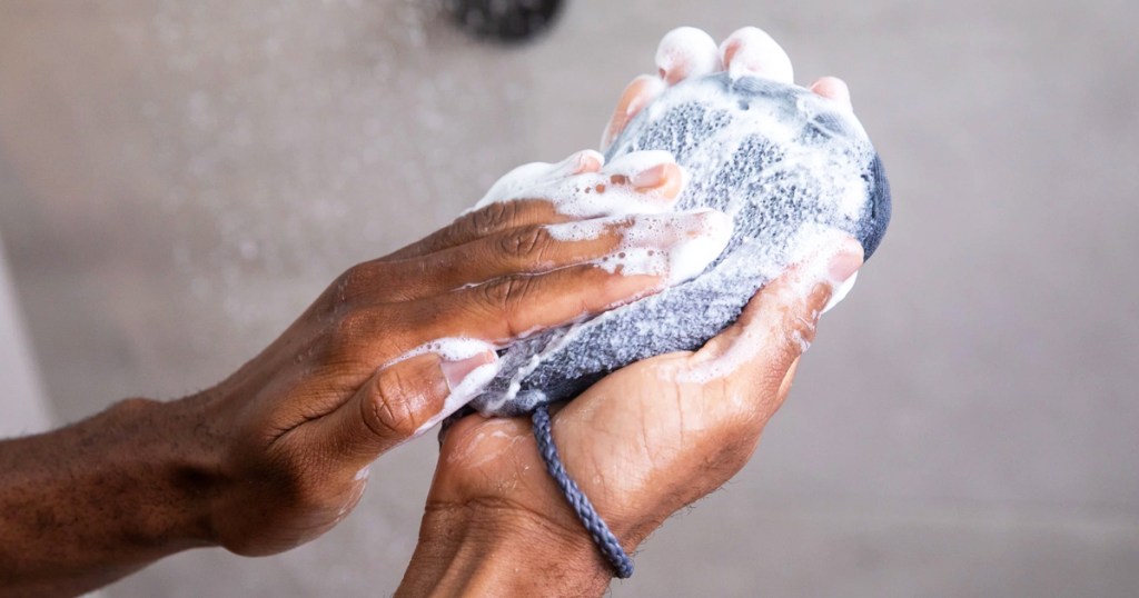 hands lathering up a soap saver in shower