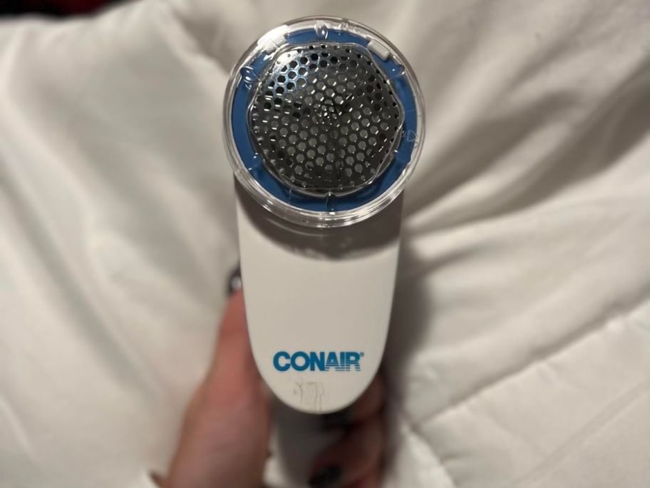 A hand holding a Conair Fabric Shaver and Lint Remover in White