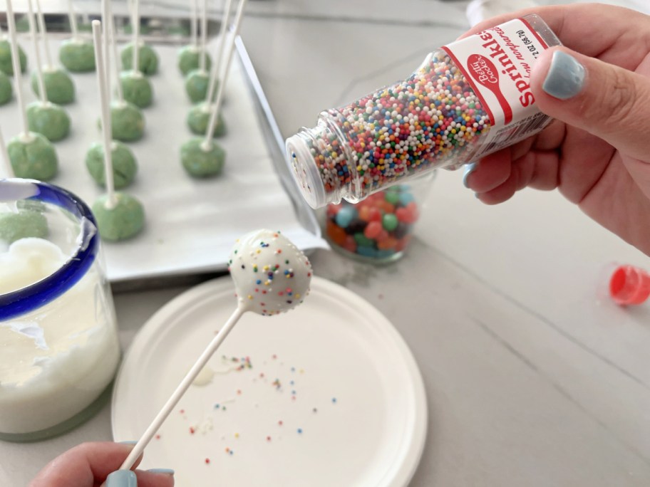 adding rainbow sprinkles to cookie pops made from leftover sugar cookies