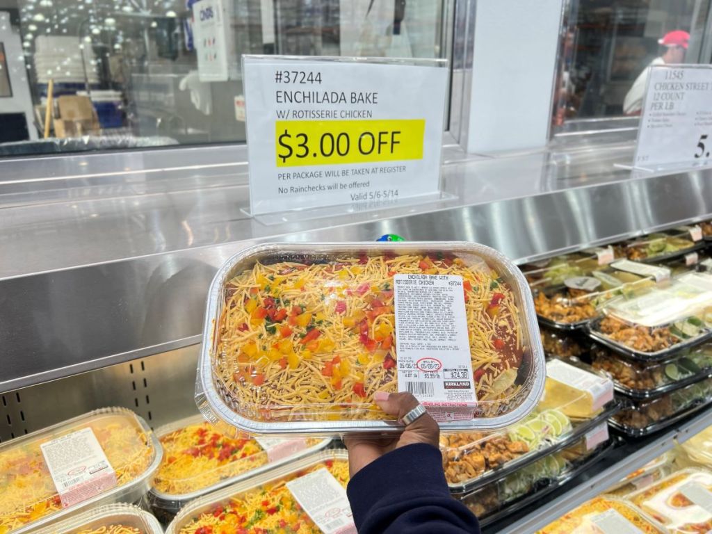 Hand holding a refrigerated enchilada bake at Costco