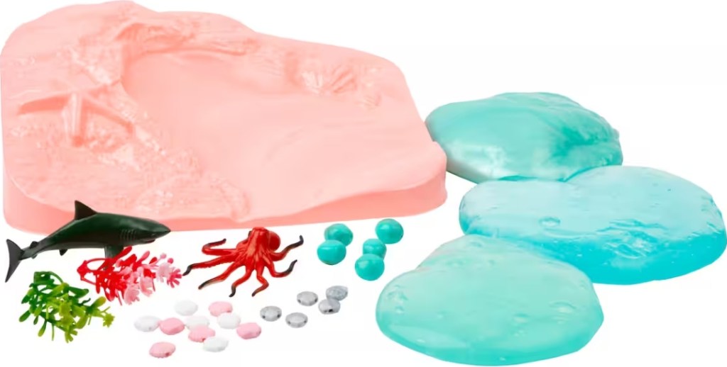 Sensory bin contents including a toy octopus, shark, seashells, and rocks