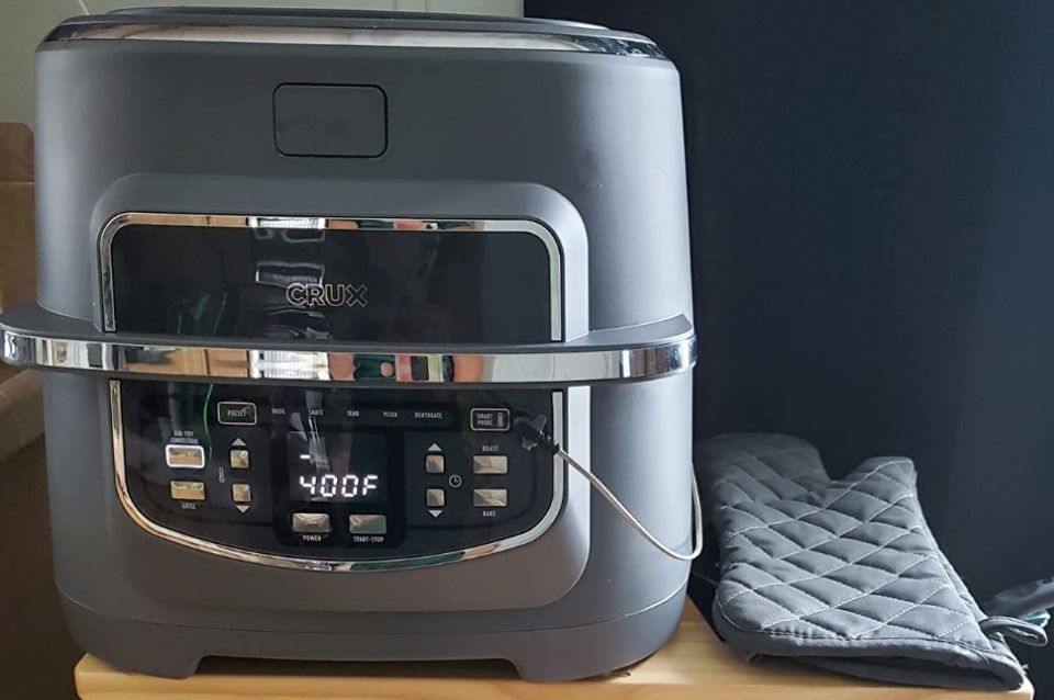 Air fryer on a table with an oven mitt next to it