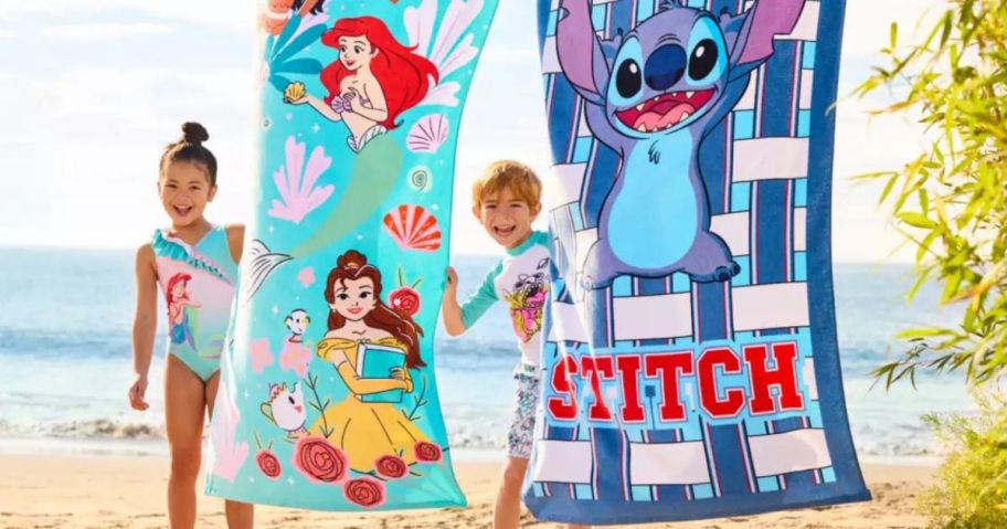 A little girl and boy next to disney themed beach towels hanging up 