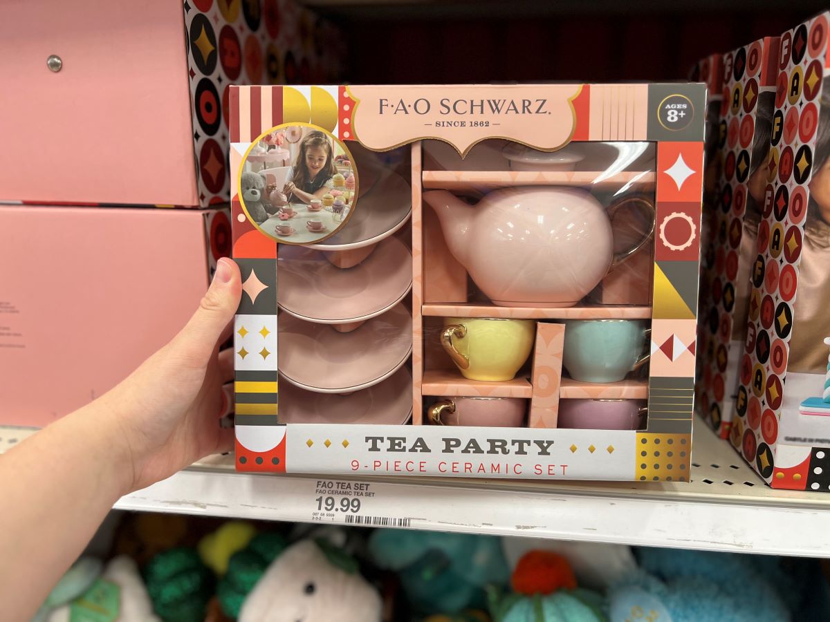 Hand holding a toy tea set box on a shelf at a store