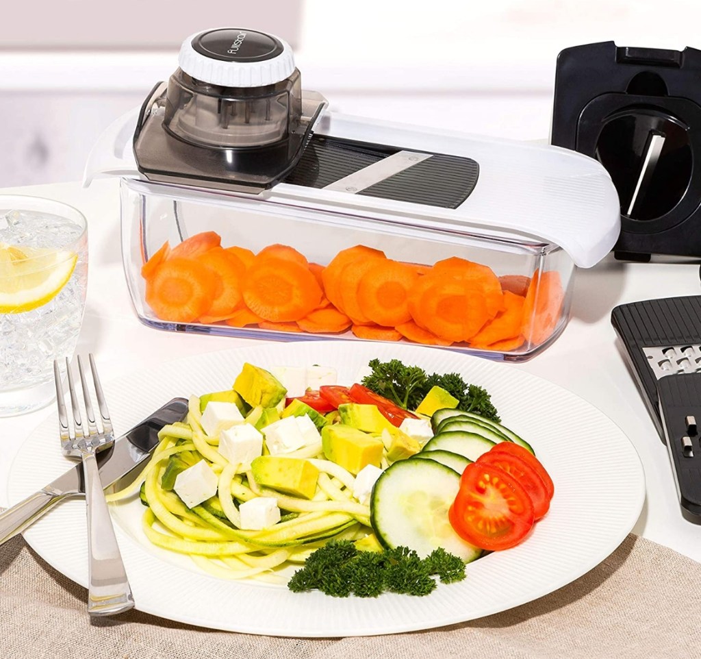 Mandoline slicer by a plate of pasta and vegetables