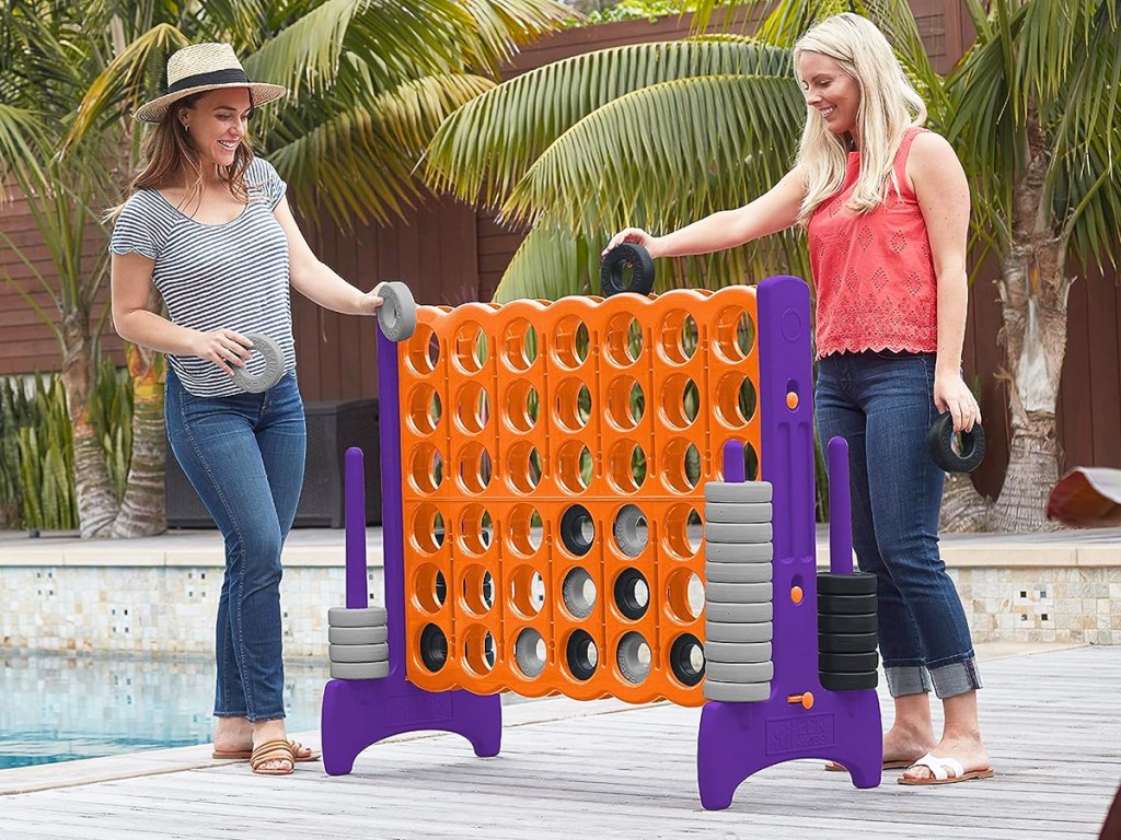 two women playing giant 4-In-A-Row Game in backyard