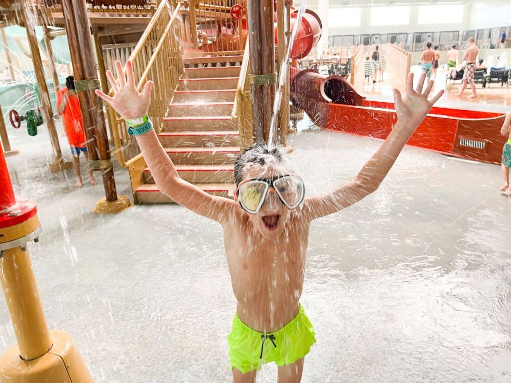 Boy at a waterpark getting water dumped on his head