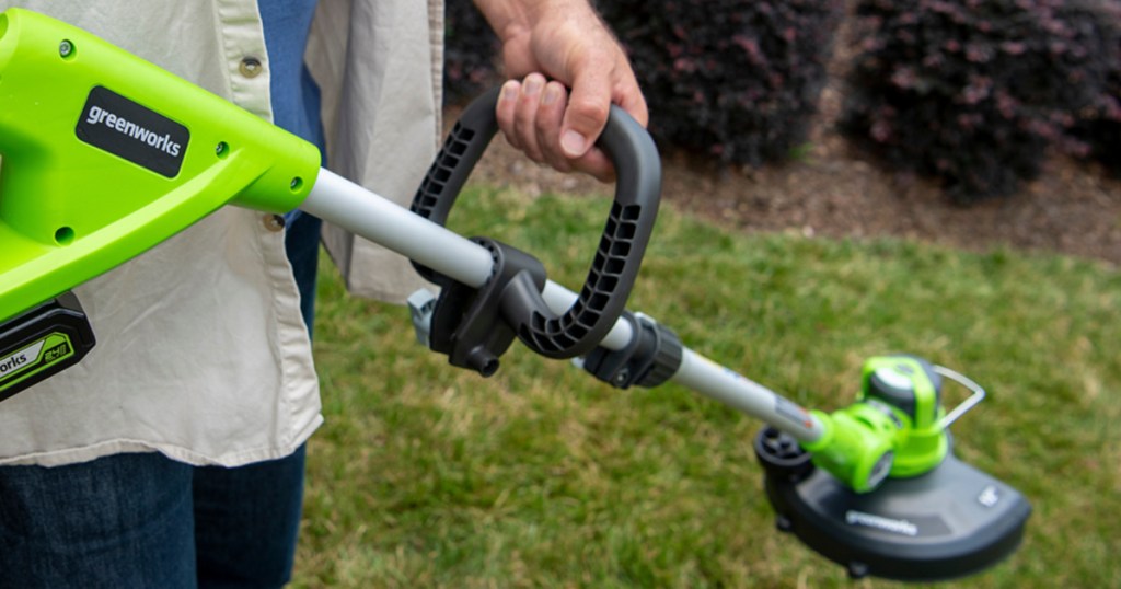 person holding greenworks edger in yard