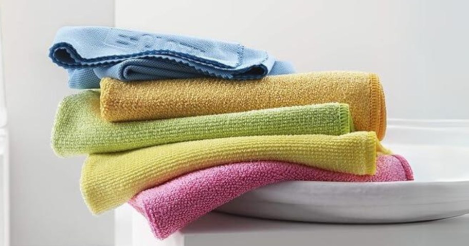 stack of 5 different color microfiber cleaning clothes on a bathroom counter