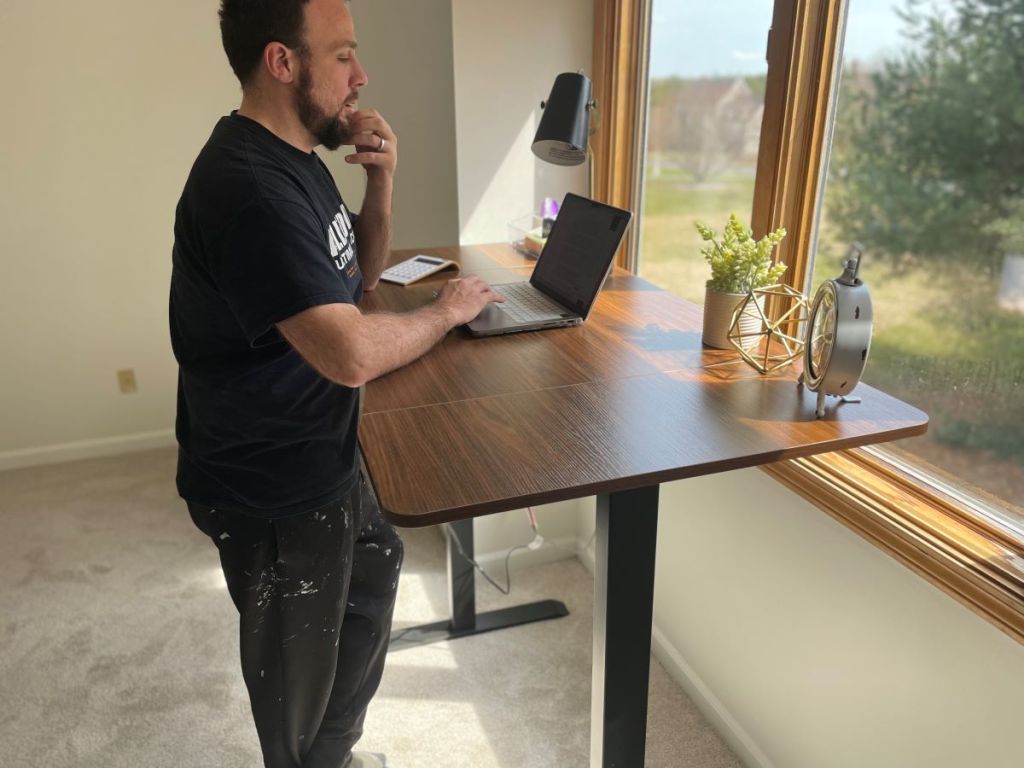 Man standing next to an electric standing desk