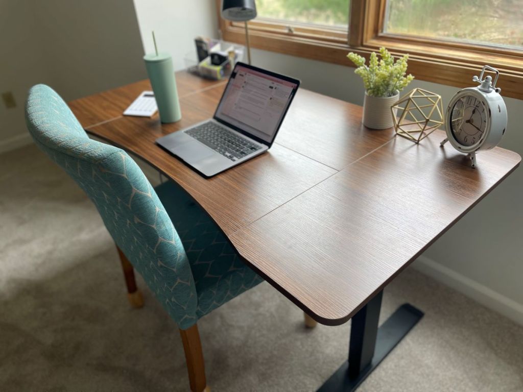 Desk with a computer on it and a teal chair next to it