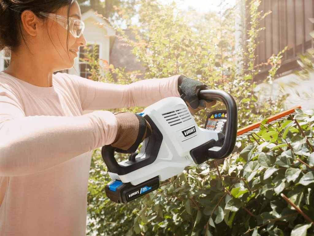 close up view of woman using Hart Hedge Trimmer to trim hedges
