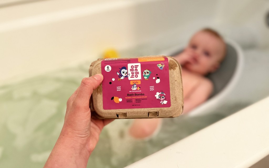 hand holding up pack of bath bombs in front of tub