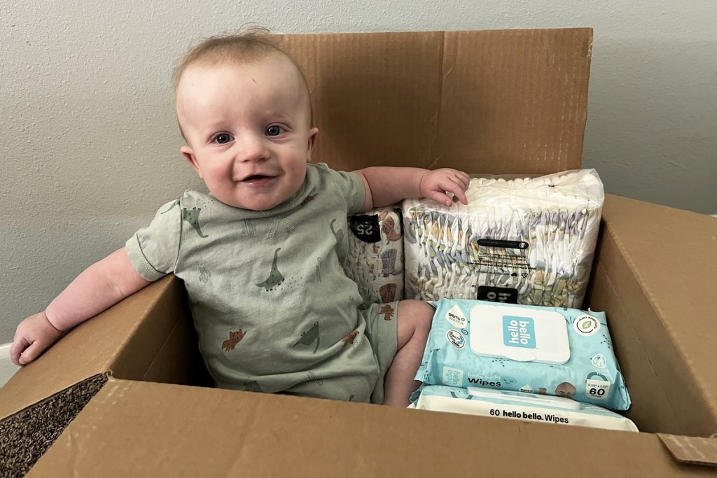 baby sitting in a box with hello bello products