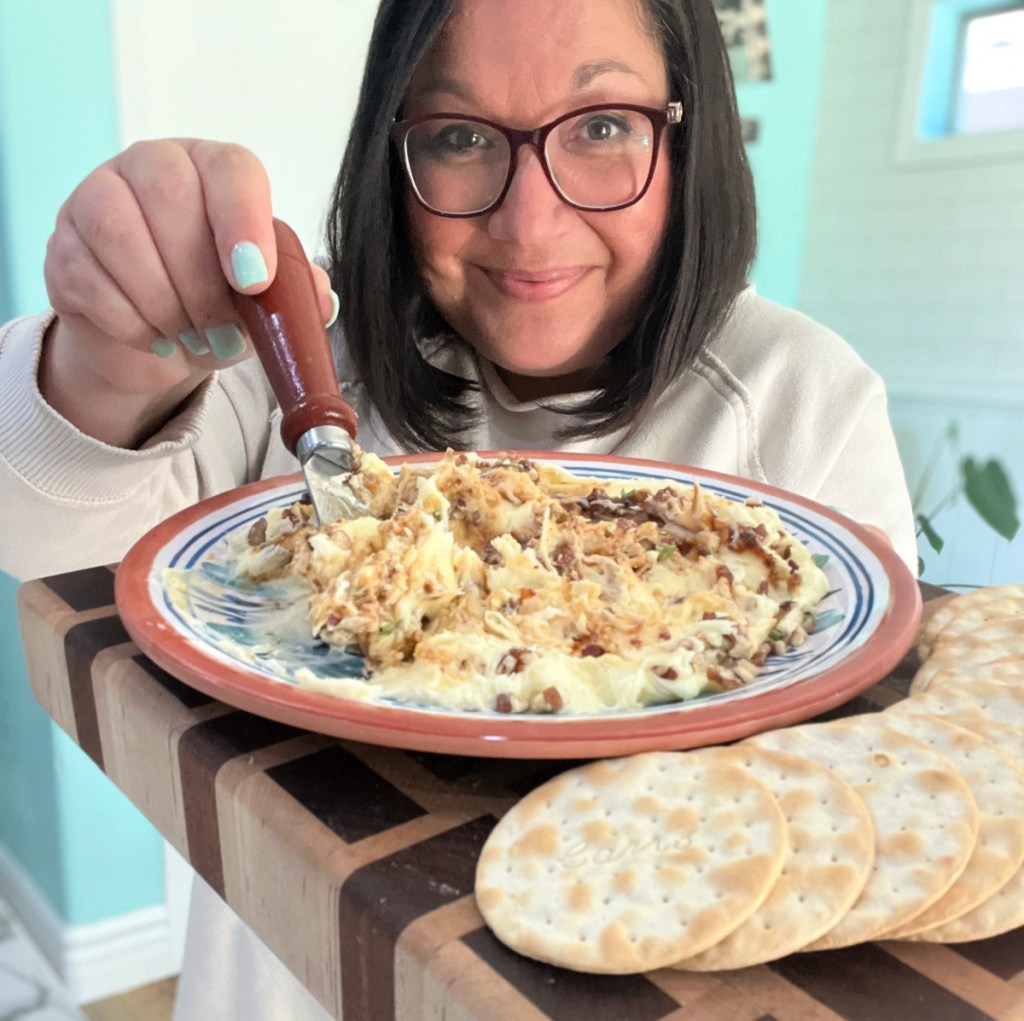 woman holding whipped feta on a plate with crackers