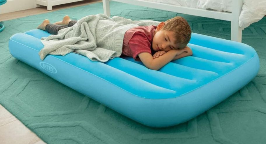 child sleeping on a blue air mattress on the floor