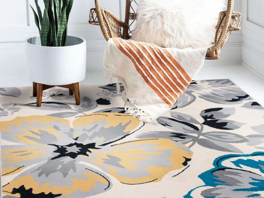 Stock image of a floral area rug with a plant and a chair set nearby