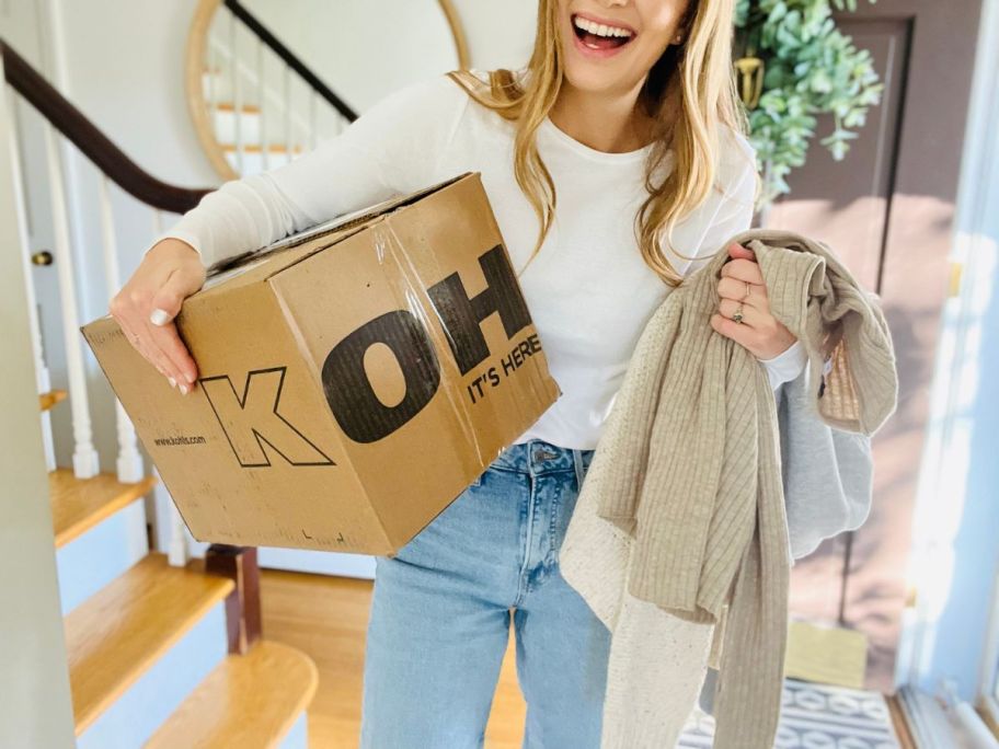 A Woman carrying a box and shirts from Kohl's